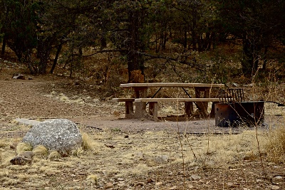 A picnic table, parking area, fire pit, and large rock
