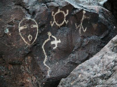 Several petroglyphs including a face on the corner of a rock
